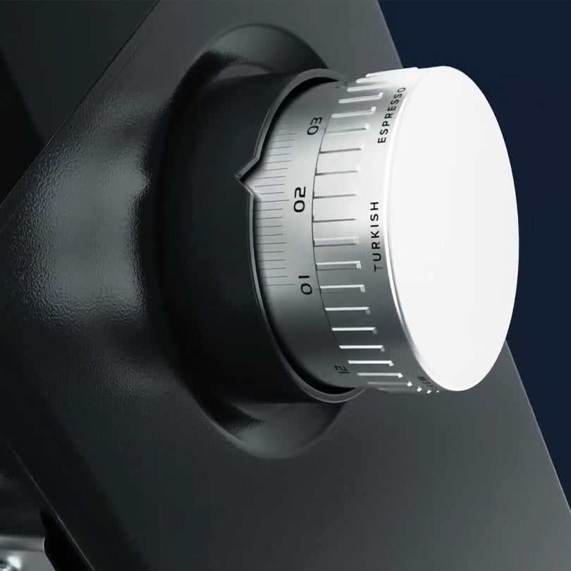 Close-up of a black and white knob with measurement scale on a dark background