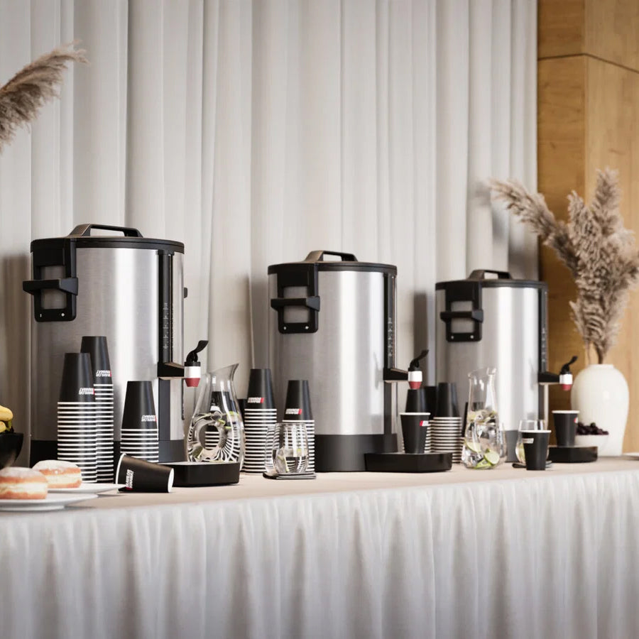 Coffee service setup with urns, cups, and saucers on a table against a striped wall.