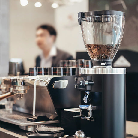 Coffee grinder with coffee beans in a coffee shop setting