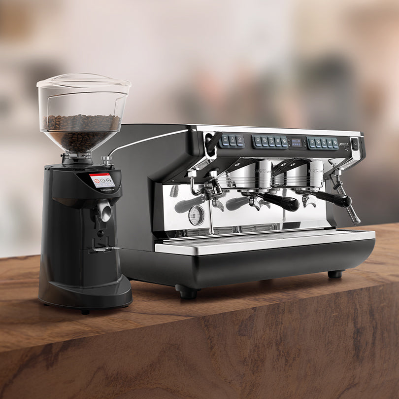 Coffee grinder and espresso machine on a wooden surface with a blurred background