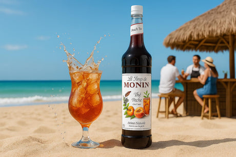 Monin syrup bottle with a glass of iced tea on a beach