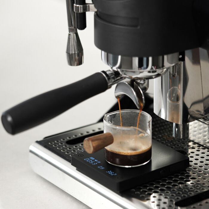Espresso machine pouring coffee into a glass on a light background