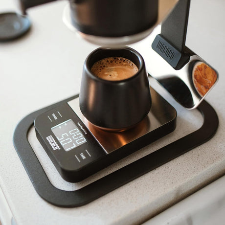 Black coffee cup on a digital scale with a blurred background