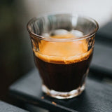 Glass of dark liquid on a blurred background