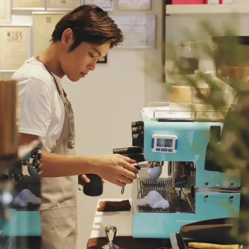 Person operating a coffee machine in a cafe setting