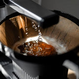 Coffee being brewed with water dripping into a coffee filter.